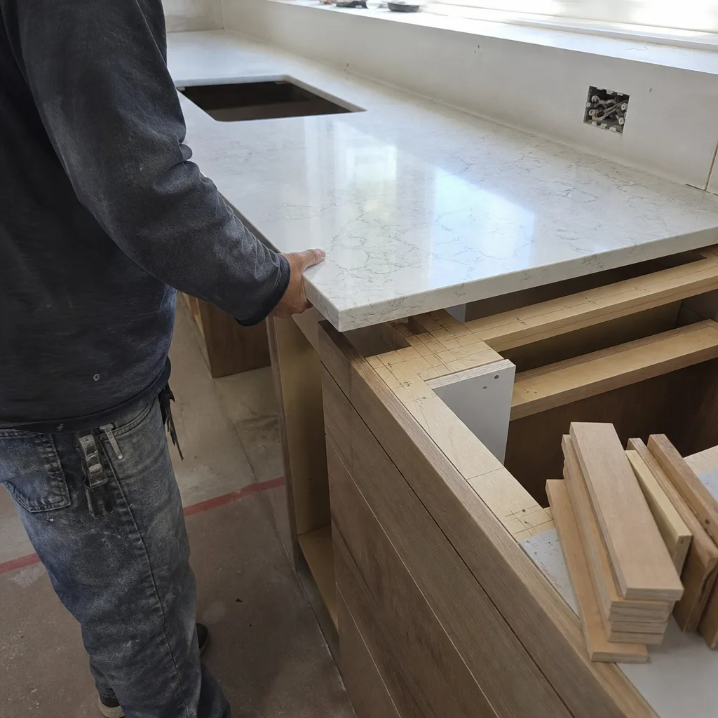 Professional contractor installing a custom quartz kitchen countertop on wooden cabinets